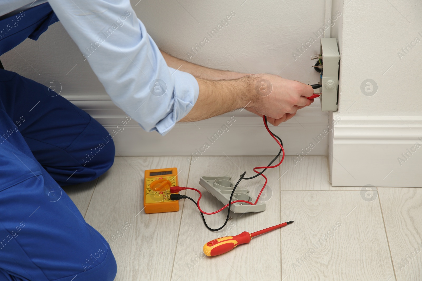 Photo of Electrician with tester checking voltage indoors, closeup