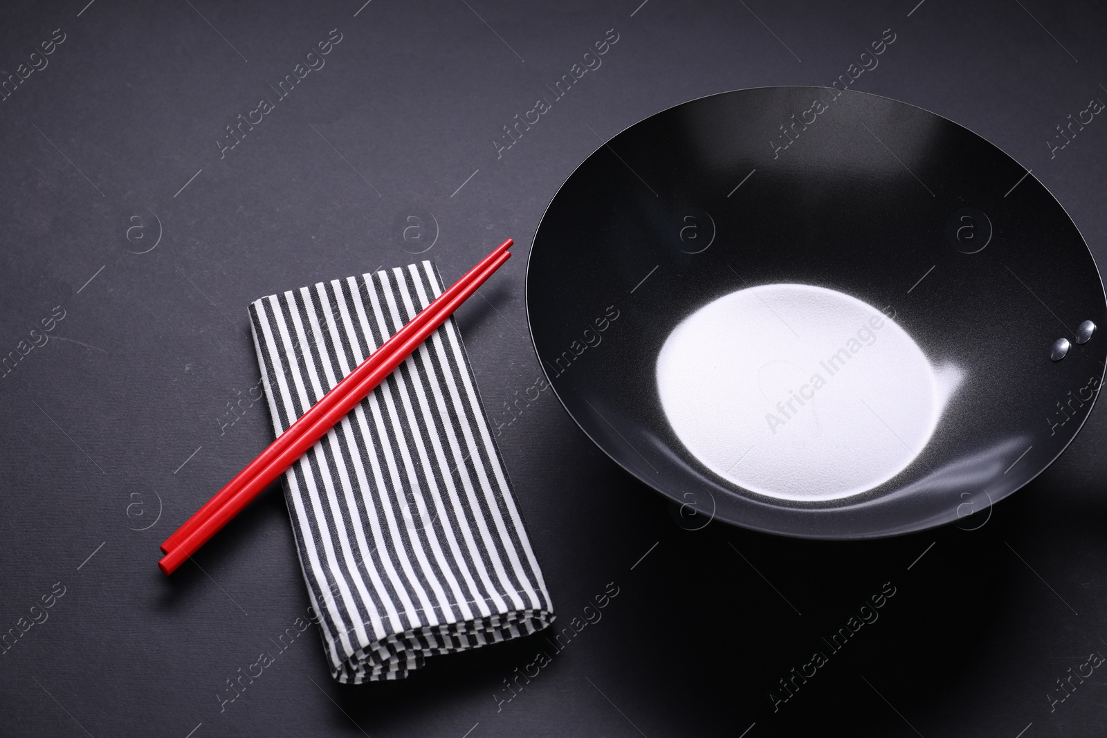 Photo of Empty iron wok and chopsticks on black table