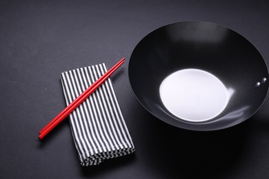 Empty iron wok and chopsticks on black table