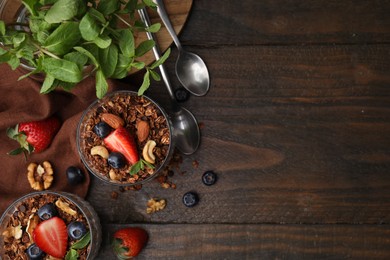 Photo of Tasty granola, berries, nuts and mint on wooden table, flat lay. Space for text