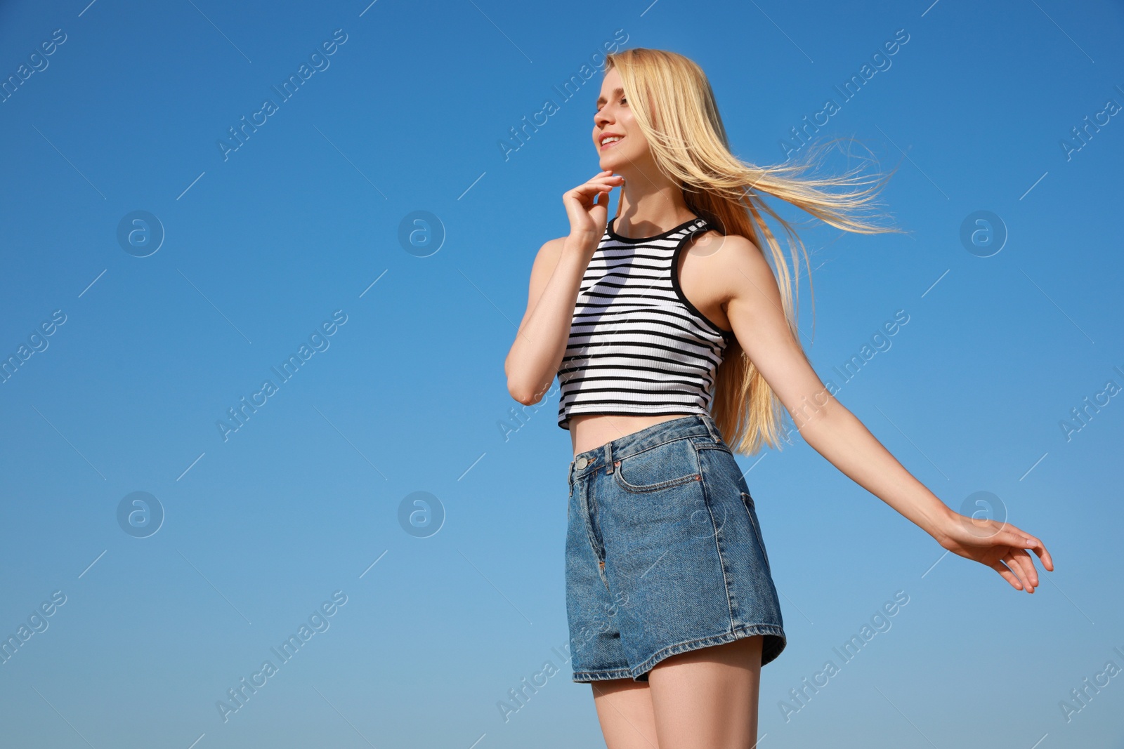 Photo of Beautiful young woman against blue sky on sunny day, space for text