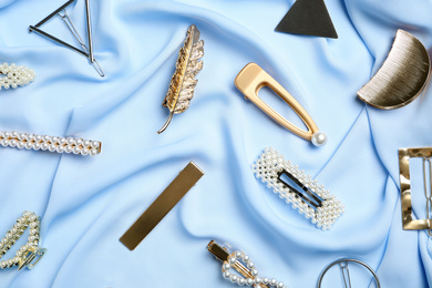 Photo of Stylish hair clips on light blue fabric, flat lay