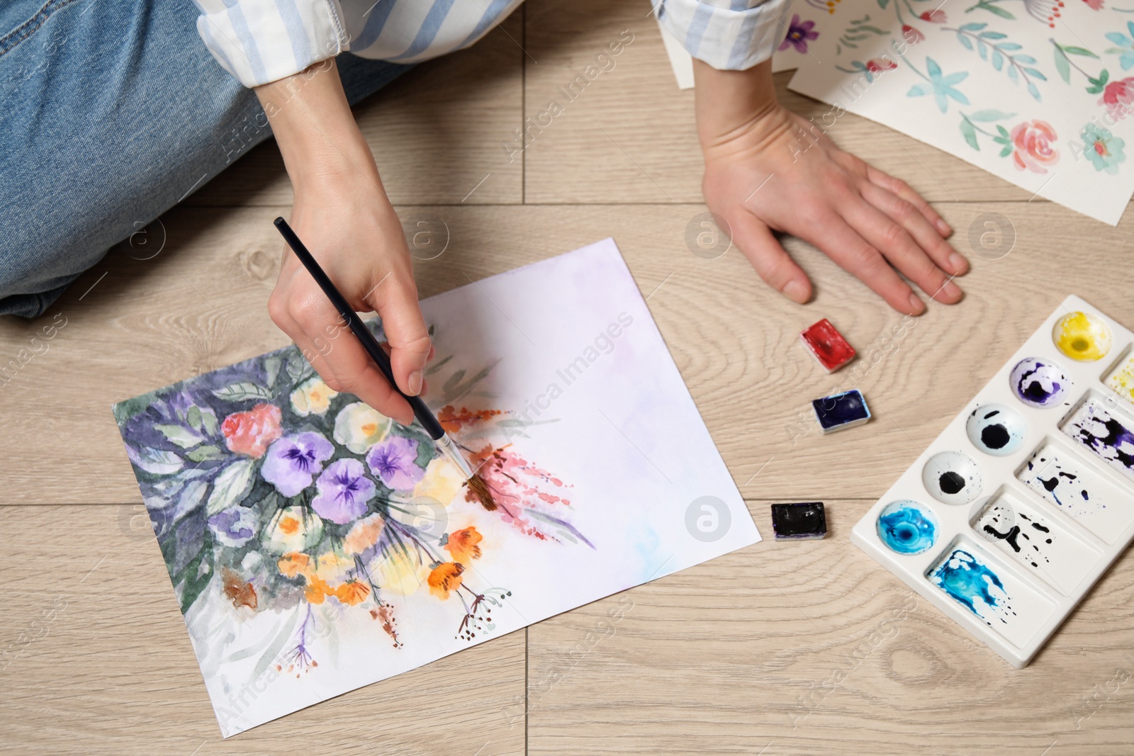 Photo of Woman painting flowers with watercolor on floor, closeup