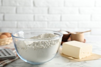 Photo of Making shortcrust pastry. Flour in bowl and butter on white marble table