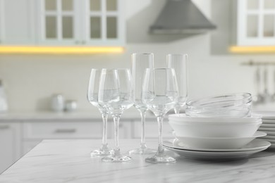 Photo of Different clean dishware and glasses on white marble table in kitchen