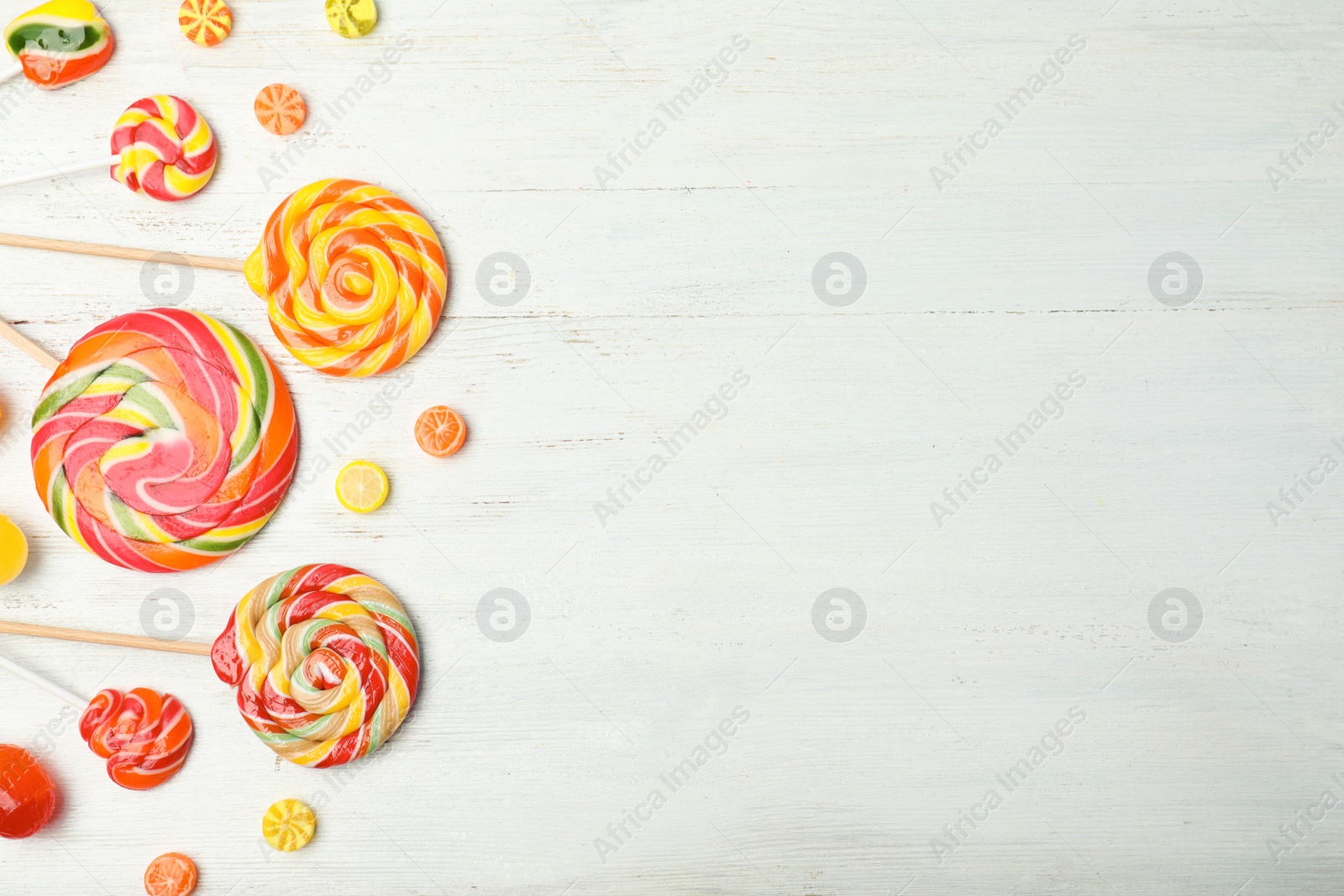 Photo of Different colorful candies and space for text on white wooden background, top view