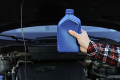 Photo of Man holding bottle of motor oil near car, closeup. Space for text