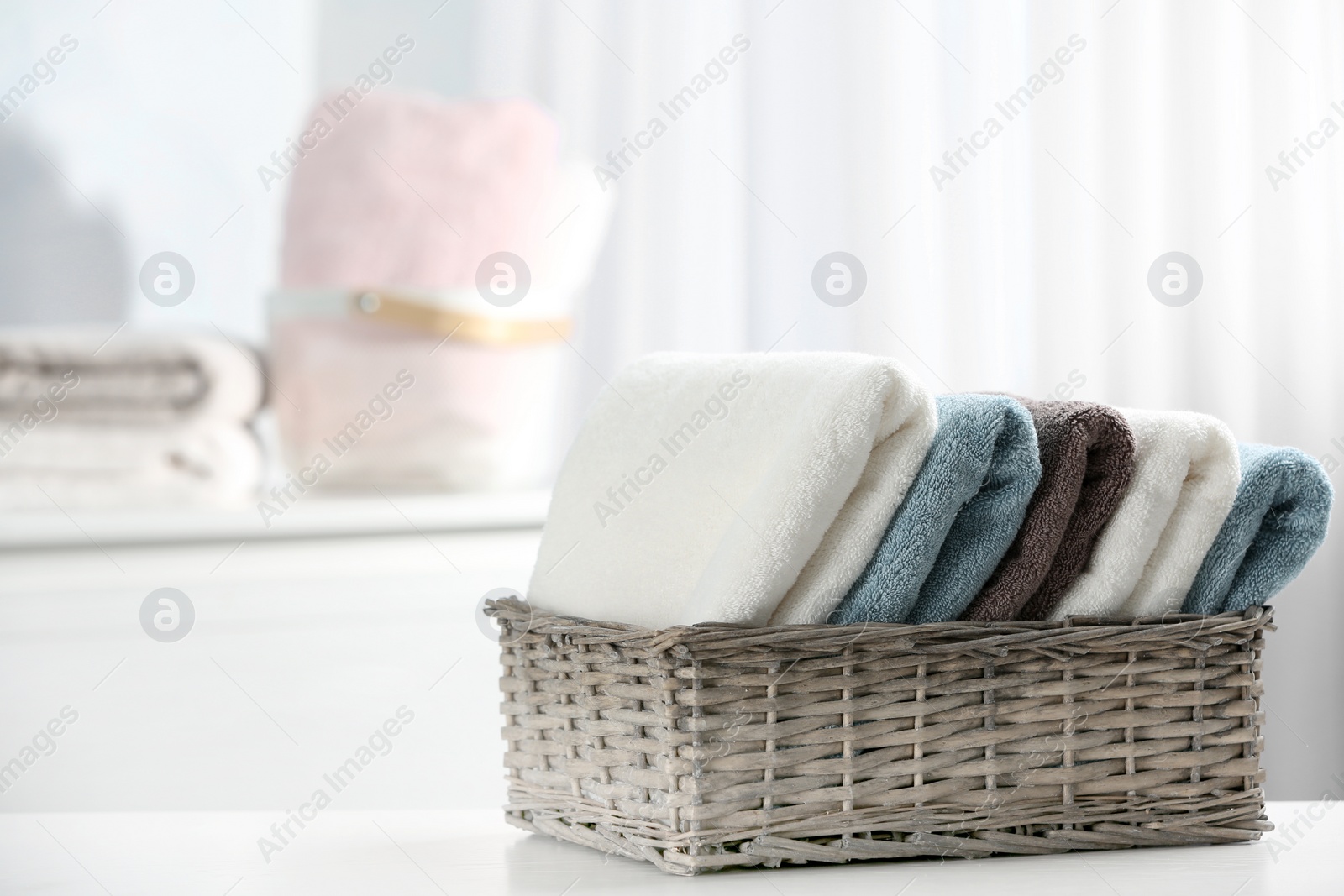 Photo of Basket of fresh towels on table. Space for text