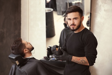 Photo of Professional hairdresser with shaving foam near client in barbershop