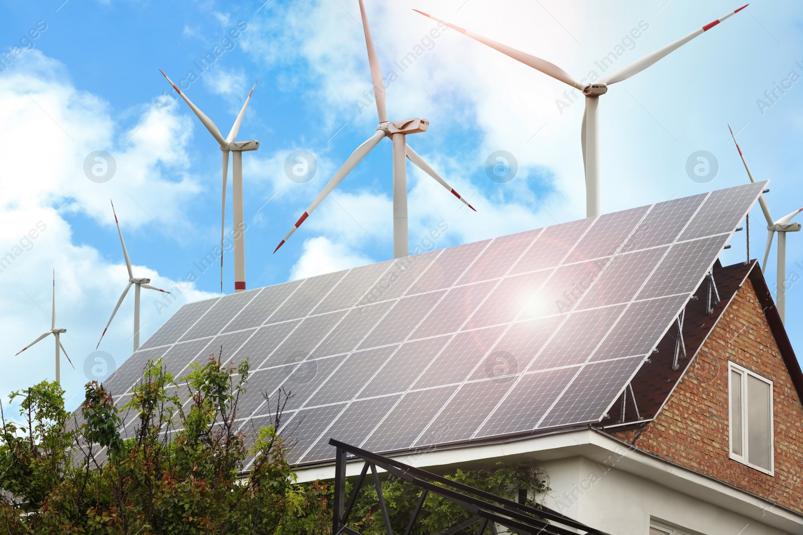 Image of Wind turbines near house with installed solar panels on roof. Alternative energy source