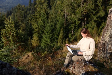 Photo of Woman working on laptop outdoors surrounded by beautiful nature