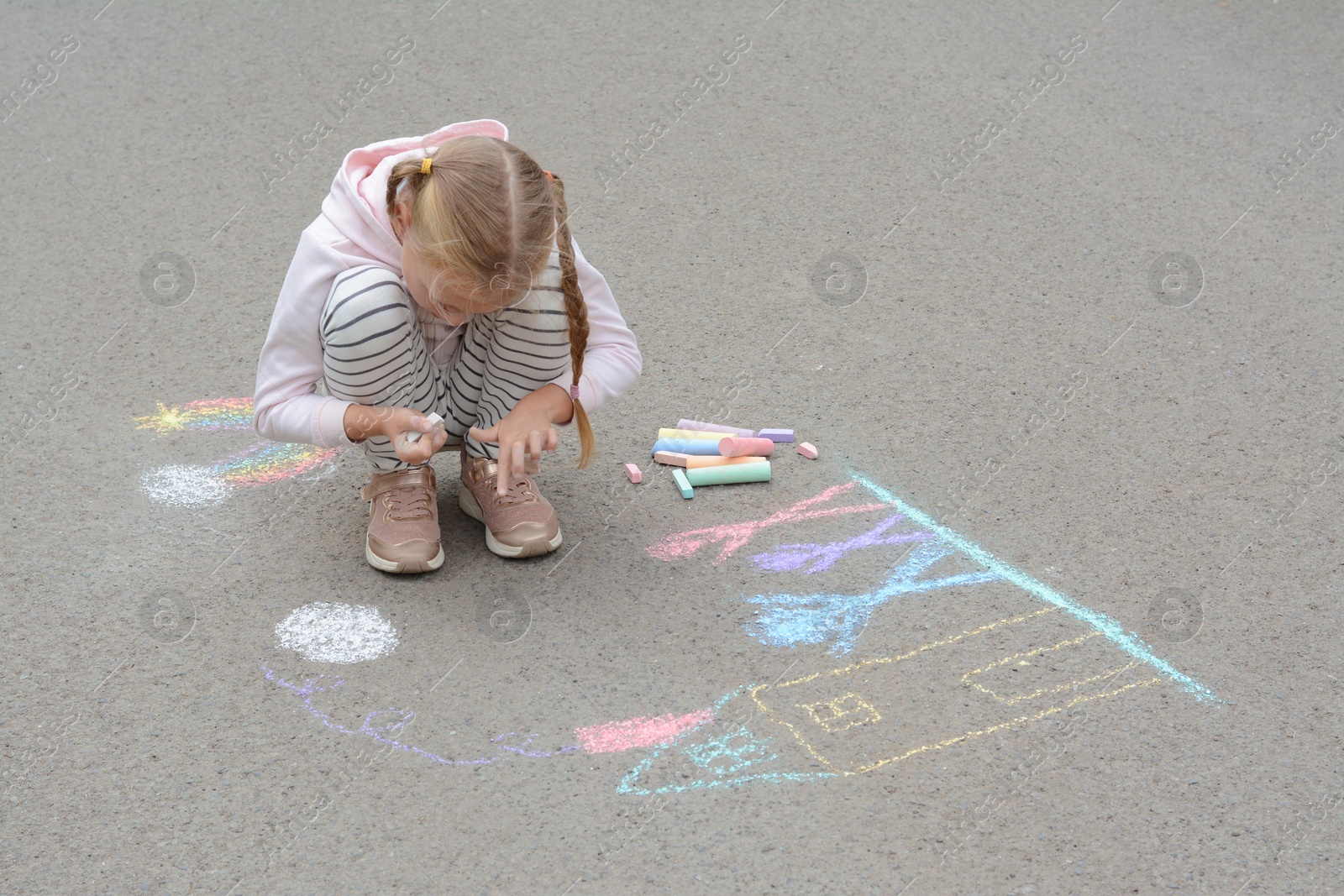 Photo of Little child drawing happy family with chalk on asphalt