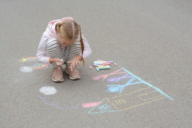 Little child drawing happy family with chalk on asphalt