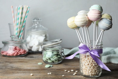 Photo of Sweet cake pops on wooden table against grey background. Space for text