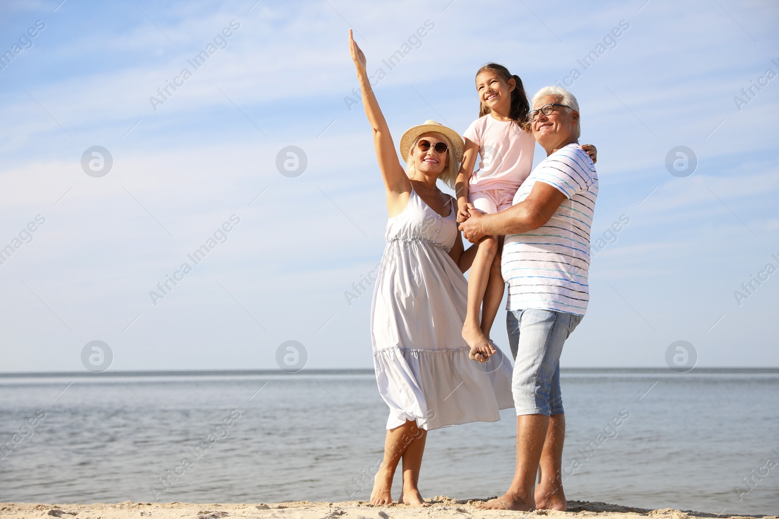Photo of Little girl with grandparents spending time together on sea beach