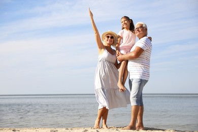 Little girl with grandparents spending time together on sea beach