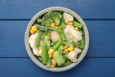Photo of Mix of different frozen vegetables in bowl on blue wooden table, top view