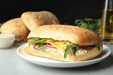 Delicious sandwich with fresh vegetables and cheese on light table