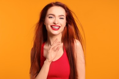 Photo of Happy woman with red dyed hair on orange background