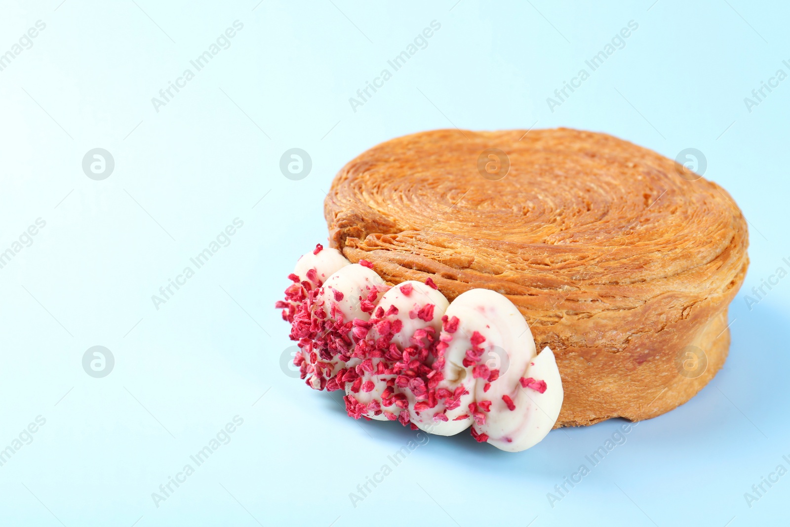 Photo of One supreme croissant with cream on light blue background, closeup with space for text. Tasty puff pastry