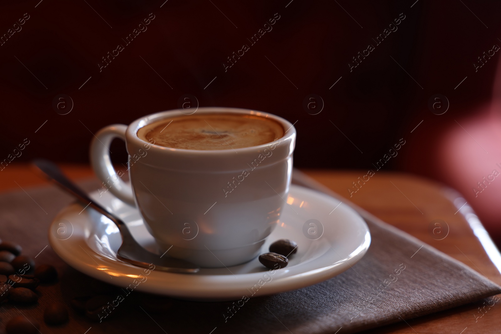 Photo of Cup of hot aromatic coffee and roasted beans on wooden table in cafe. Space for text