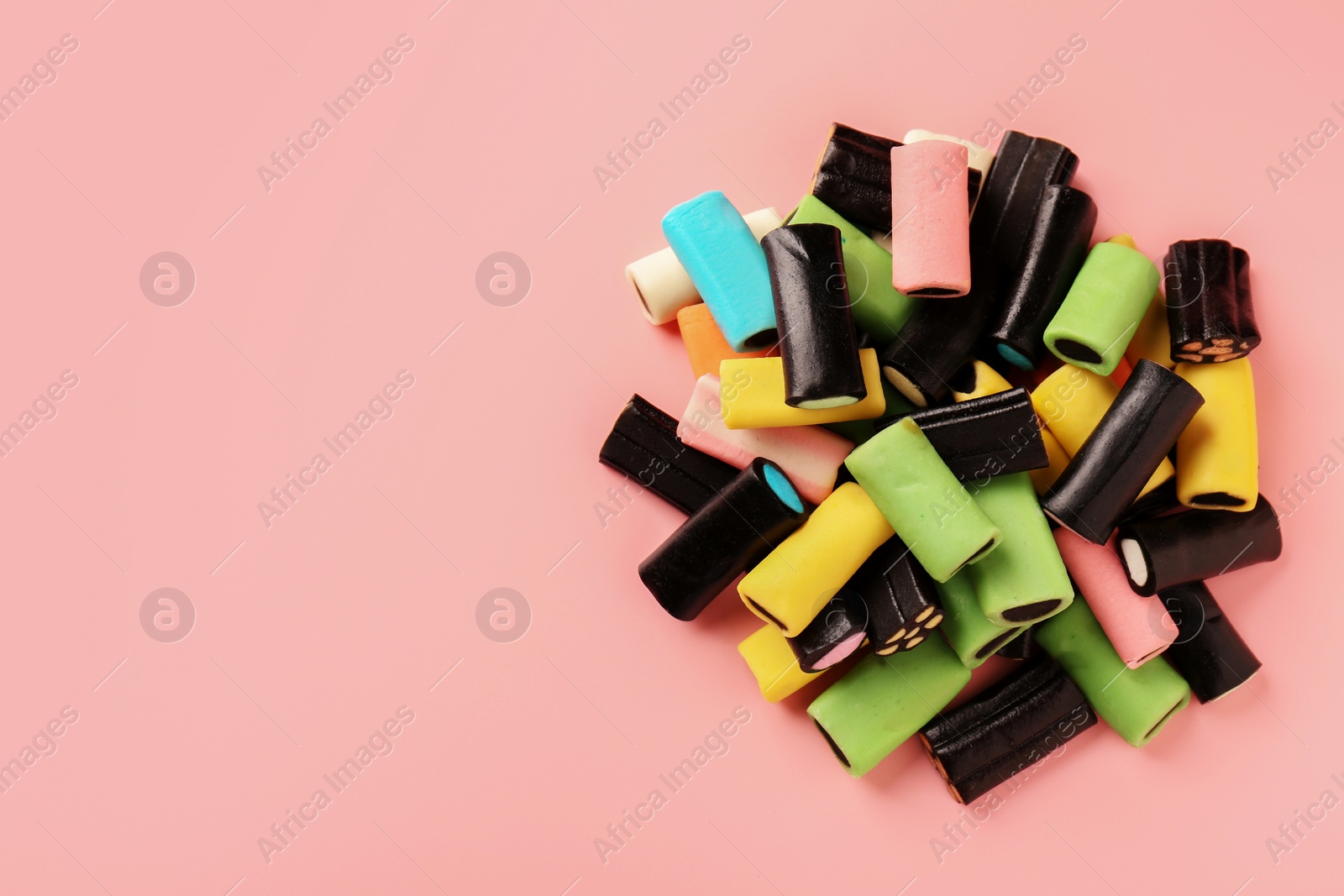 Photo of Many tasty liquorice candies on pink background, top view. Space for text