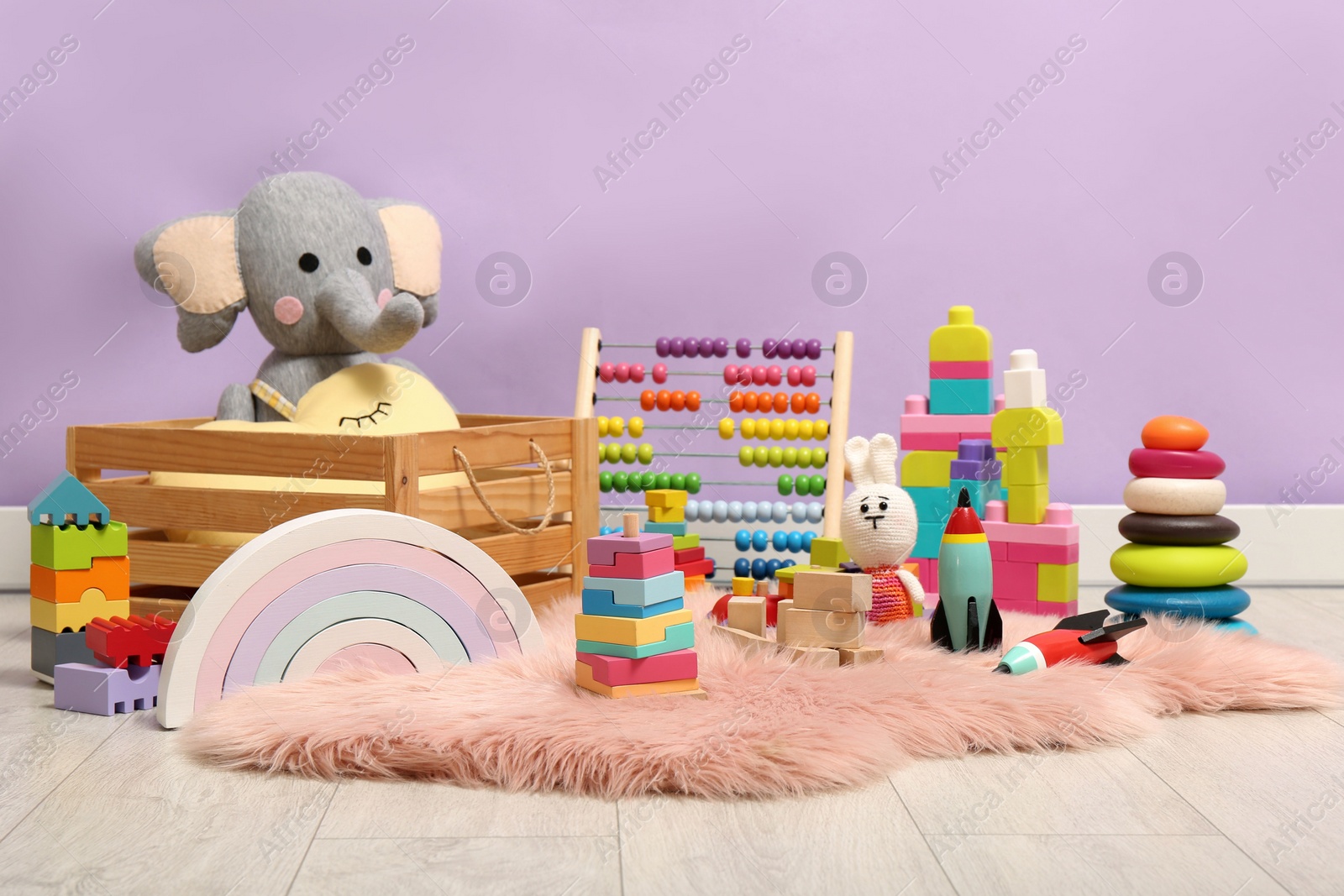 Photo of Set of different toys on rug near violet wall