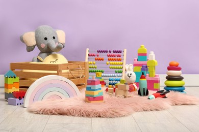 Photo of Set of different toys on rug near violet wall