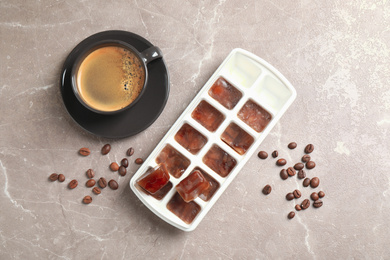 Ice cubes, cup of coffee and beans on grey table, flat lay