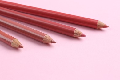 Lip pencils on pink background, closeup. Cosmetic product