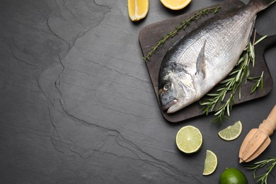 Photo of Flat lay composition with fresh raw dorado fish and ingredients on black table, space for text