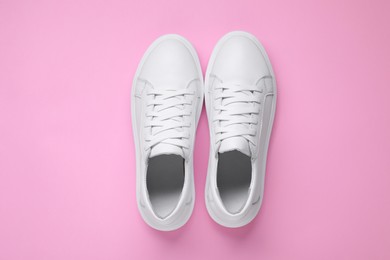 Photo of Pair of stylish white sneakers on pink background, top view