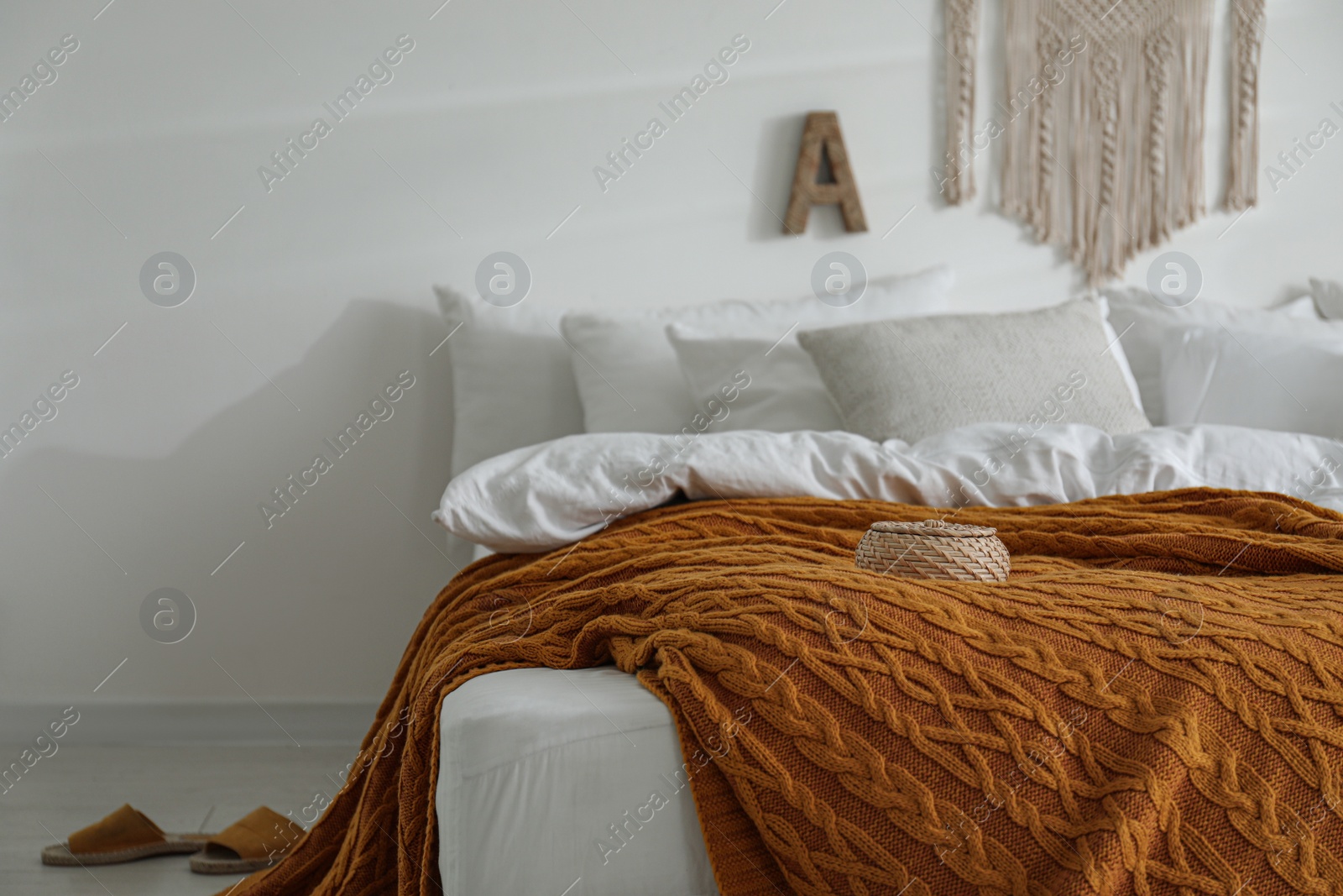 Photo of Warm orange knitted plaid on bed indoors