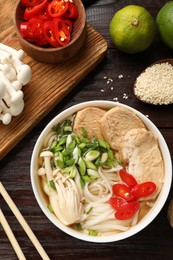 Photo of Delicious ramen with meat and ingredients on wooden table, flat lay. Noodle soup