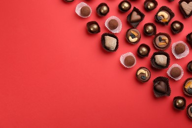 Photo of Different delicious chocolate candies on red background, flat lay. Space for text