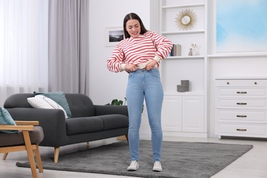 Photo of Woman trying to put on tight jeans at home