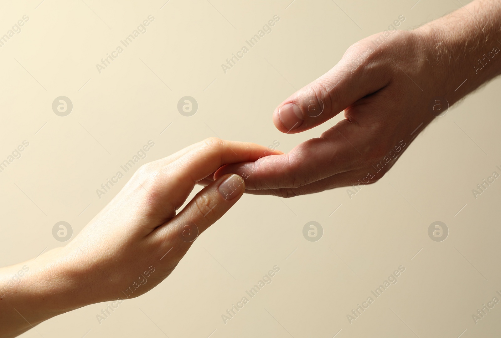 Photo of Man and woman holding hands together on beige background, closeup