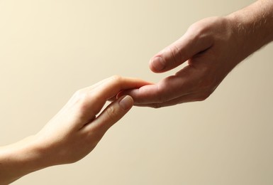 Photo of Man and woman holding hands together on beige background, closeup