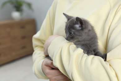 Photo of Woman with cute fluffy kitten at home, closeup
