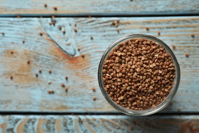 Photo of Uncooked buckwheat in glass on table, top view. Space for text