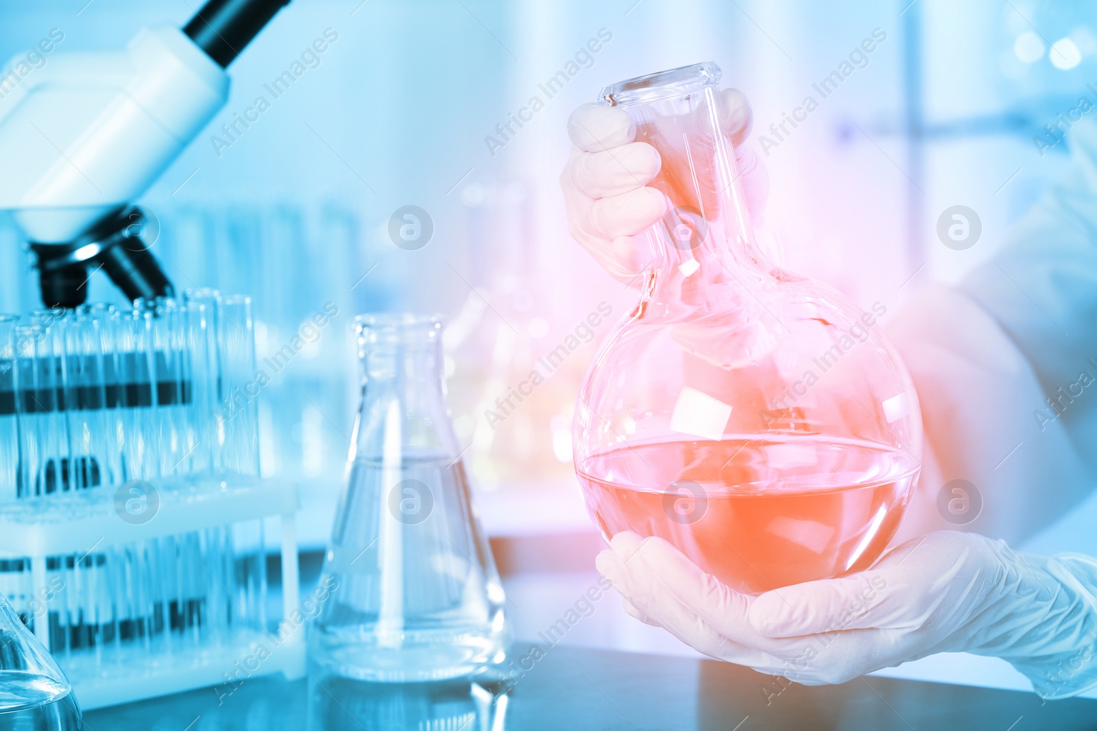 Image of Scientist holding Florence flask with liquid at table, closeup. Laboratory analysis