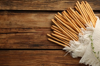 Delicious grissini sticks with napkin on wooden table, top view. Space for text