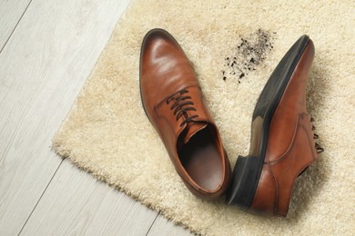 Photo of Brown shoes and mud on beige carpet, top view. Space for text