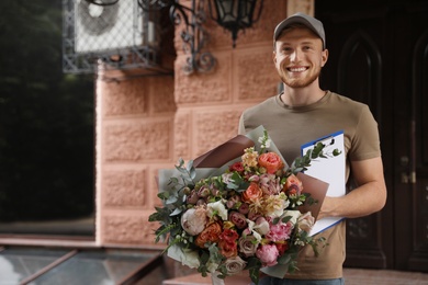 Happy delivery man with beautiful flower bouquet outdoors