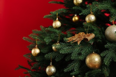 Photo of Beautifully decorated Christmas tree on red background, closeup