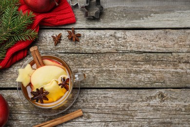 Photo of Hot mulled cider and ingredients on wooden table, flat lay. Space for text