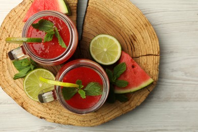 Photo of Tasty summer watermelon drink, limes and mint on white wooden table, top view