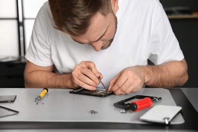 Technician repairing mobile phone at table in workshop