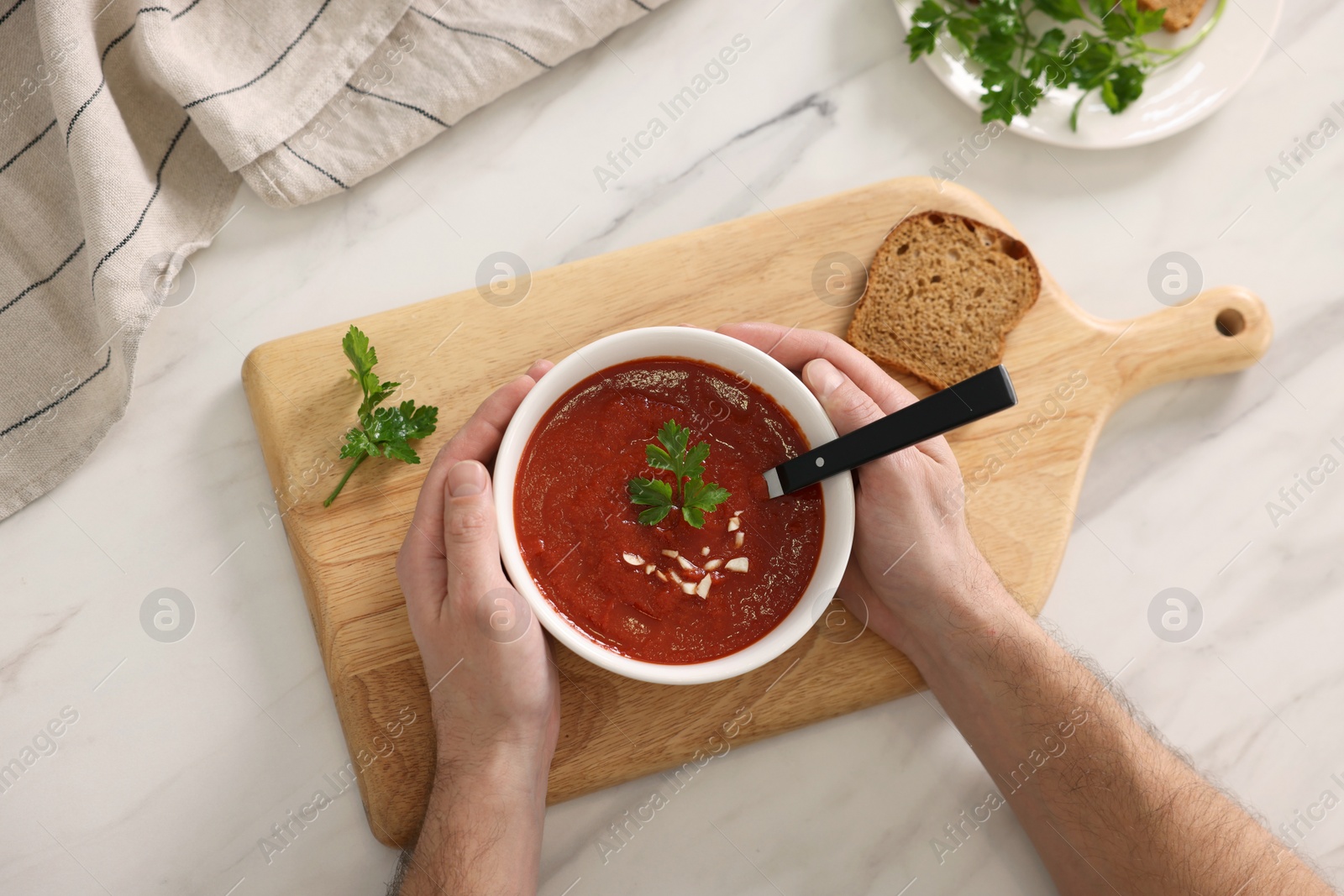 Photo of Man with delicious tomato soup at light marble table, top view