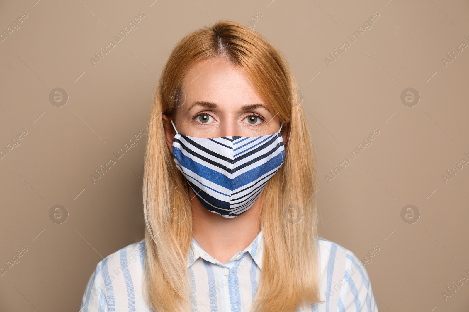 Photo of Woman wearing handmade cloth mask on beige background. Personal protective equipment during COVID-19 pandemic